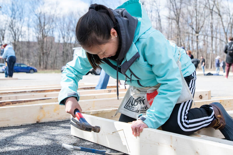 An R I T student helping build a frame for a house during a Habitat for Humanity volunteer event.