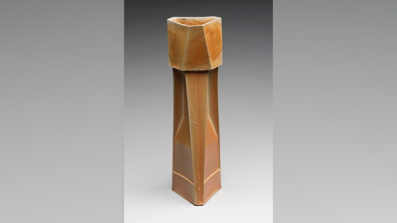 A tall wooden sculpture inspired by industrial architecture.